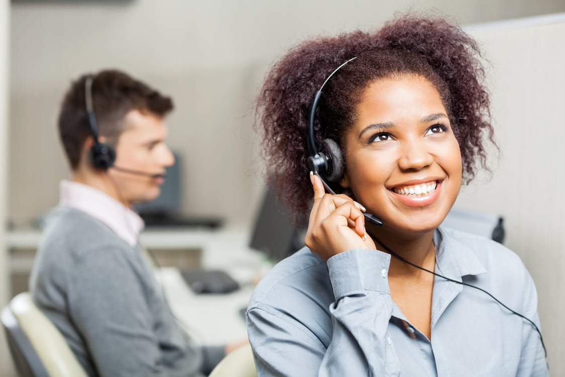 Happy Female Call Center Agent Using Headset in Call Center